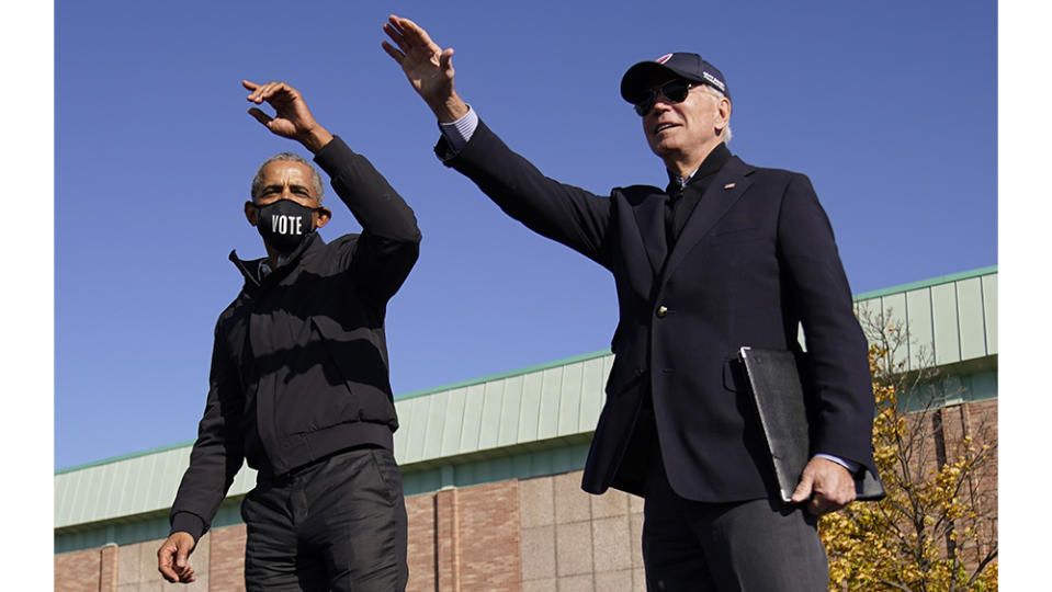 Democratic presidential candidate former Vice President Joe Biden, right, and former President Barack Obama, left, on stage together waving to the audience at a rally at Northwestern High School in Flint, Mich., Saturday, Oct. 31, 2020. (AP Photo/Andrew Harnik)