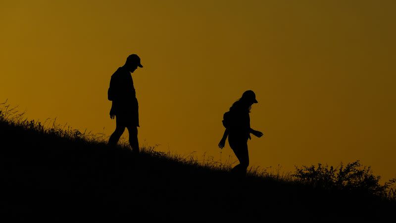 A couple walk through a park at sunset, Monday, July 17, 2023, in San Antonio. Triple-digit temperatures and heat advisories are expected throughout the week, so getting sleep can be a challenge.