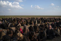 Men wait to be screened by U.S.-backed Syrian Democratic Forces (SDF) fighters after being evacuated out of the last territory held by Islamic State militants, near Baghouz, eastern Syria, Friday, Feb. 22, 2019. (AP Photo/Felipe Dana)