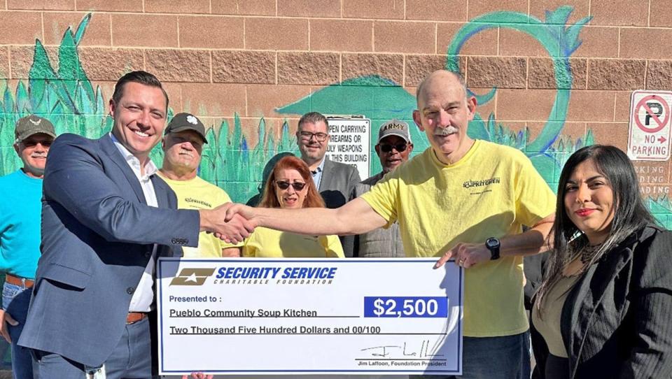 Brandon Blanchard (left), senior vice president of member service for Security Service Federal Credit Union's mountain region and Sarah Blaher (right) assistant branch manager, present a $2,500 check to Jim Concialdi, board president, and some of the volunteers at Pueblo Community Soup Kitchen.