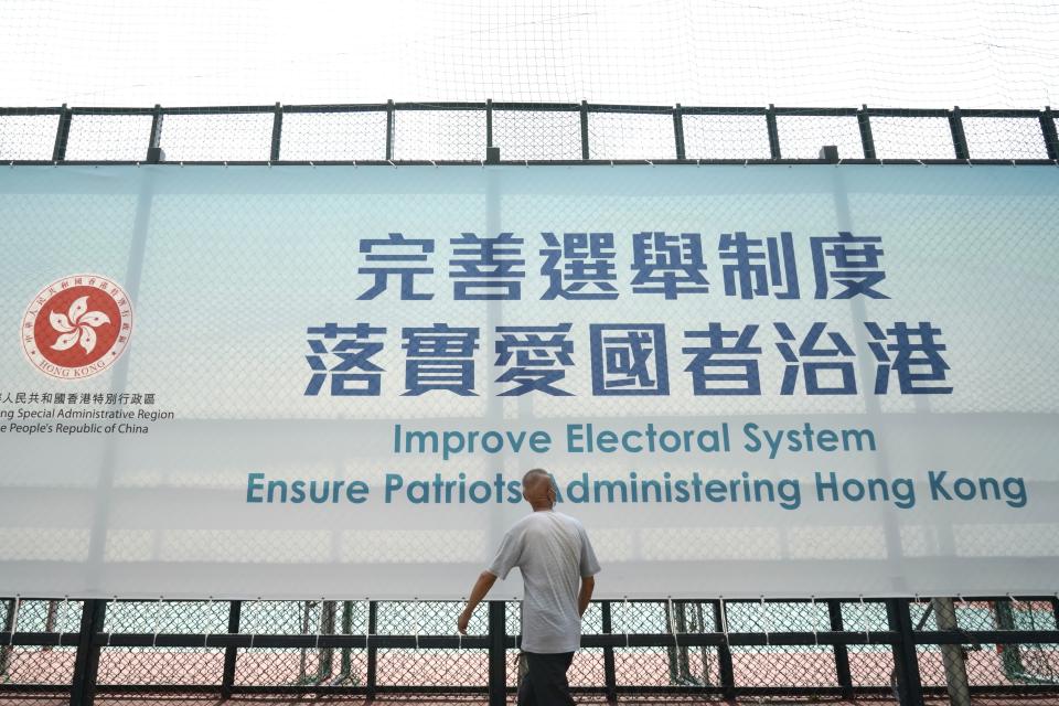 A man walks past a government advertisement to promote the new Hong Kong electoral system reform, in Hong Kong, March 30, 2021. China's top legislature approved amendments to Hong Kong's constitution on Tuesday that will give Beijing more control over the make-up of the city's legislature. (AP Photo/Kin Cheung)