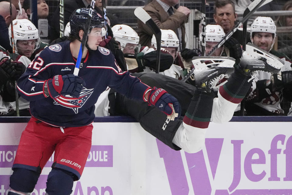 Arizona Coyotes' Michael Kesserlring, right, falls into the bench after attempting to check Columbus Blue Jackets' Alexandre Texier (42) during the first period of an NHL hockey game Thursday, Nov. 16, 2023, in Columbus, Ohio. (AP Photo/Sue Ogrocki)