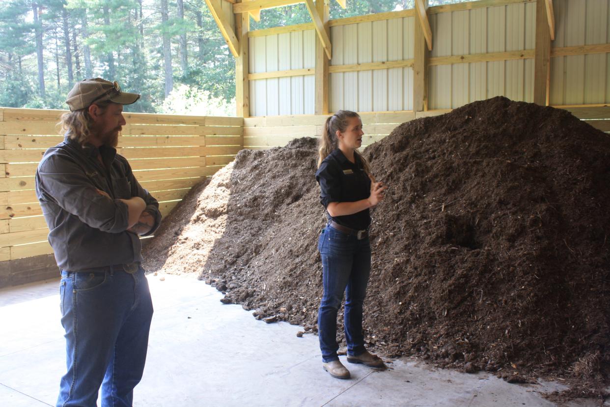 Eli Winkenwerder and fellow Natural Resources Coordinator Kimber Jones stand beside a pile of compost