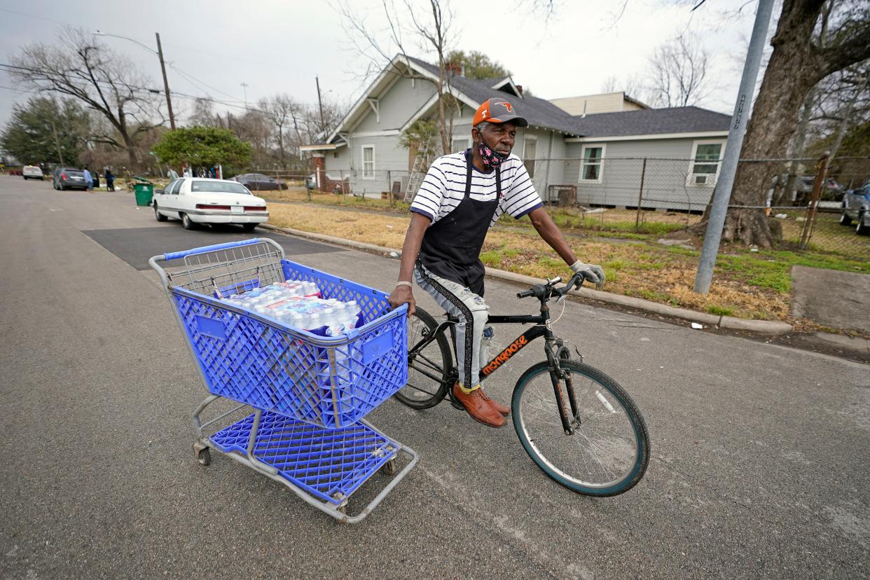 Fifth Ward resident Mark Johnson pulls a shopping cart with donated water back to his apartment, which still does not have running water, Friday, Feb. 26, 2021, in Houston. President Joe Biden and his wife Jill are visiting Houston Friday to survey damage caused by severe winter weather and encourage people to get their coronavirus shots. At least 40 people died in Texas as a result of the storm and more than 1 million residents are still under a boil water notice. 