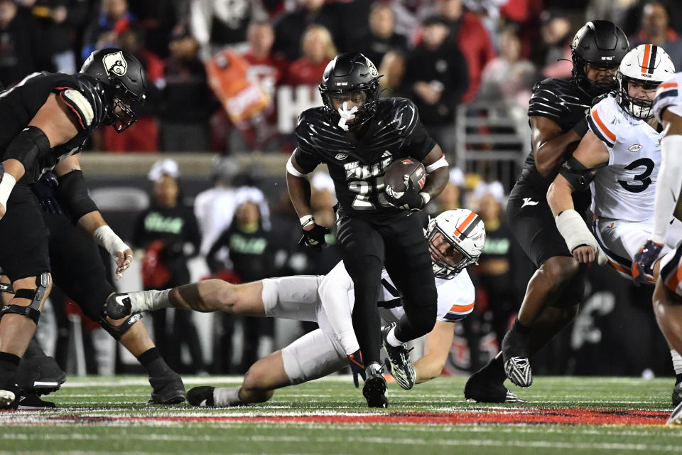 Louisville running back Jawhar Jordan, center top, runs away from a tackle-attempt by Virginia linebacker James Jackson (7) during the second half of an NCAA college football game in Louisville, Ky., Thursday, Nov. 9, 2023. (AP Photo/Timothy D. Easley)