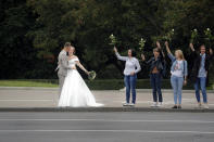 A newly wed couple kiss as Belarusian opposition supporters hold flowers during a protest in Minsk, Belarus, Thursday, Aug. 20, 2020. Demonstrators are taking to the streets of the Belarusian capital and other cities, keeping up their push for the resignation of the nation's authoritarian leader. President Alexander Lukashenko has extended his 26-year rule in a vote the opposition saw as rigged. (AP Photo/Dmitri Lovetsky)