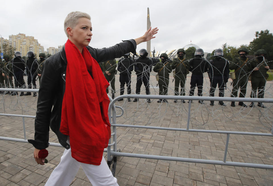 Maria Kolesnikova, one of opposition leaders, walks past riot policemen blocking the streets during protests in Minsk, Belarus, Sunday, Aug. 23, 2020. More than 100,00 protesters demanding the resignation of Belarus' authoritarian president are rallying in a vast square in the capital, continuing the massive outburst of dissent that has shaken the country since dubious presidential elections two weeks ago. (AP Photo/Dmitri Lovetsky)