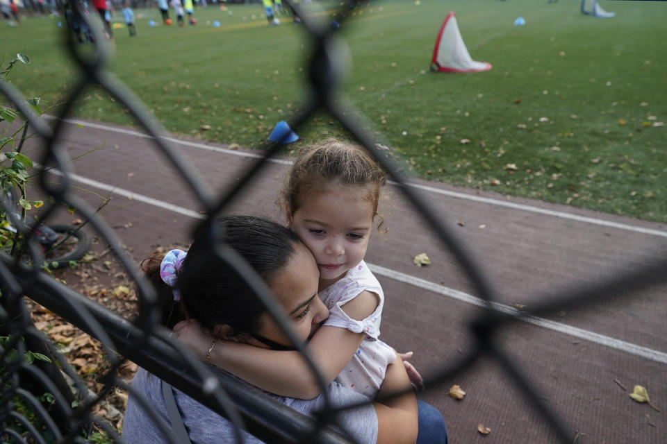 A woman embraces her young daughter as they spend time outdoors at a public park in the Gravesend section of Brooklyn, Monday, Sept. 28, 2020, in New York. The neighborhood has seen a recent uptick in COVID-19 cases. New York Gov. Andrew Cuomo raised alarms Monday about the emergence of a handful of coronavirus hot spots in New York, including the Gravesend neighborhood, saying just 10 ZIP codes represented more than a quarter of the state's new infections in recent testing. (AP Photo/Kathy Willens)