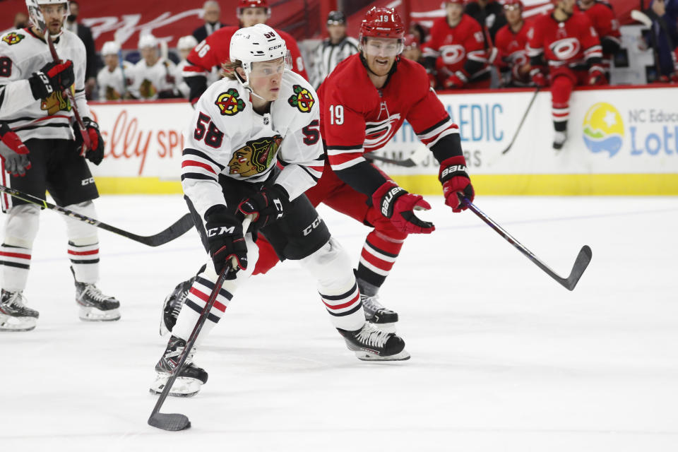 Chicago Blackhawks' MacKenzie Entwistle (58) moves the puck past Carolina Hurricanes' Dougie Hamilton (19) during the first period of an NHL hockey game in Raleigh, N.C., Thursday, May 6, 2021. (AP Photo/Karl B DeBlaker)