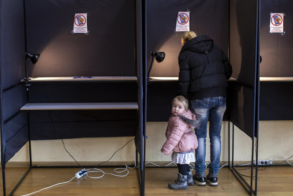 A child looks out of booth at a polling station during the second round of a parliamentary election in Vilnius, Lithuania, Sunday, Oct. 25, 2020. Polls opened Sunday for the run-off of national election in Lithuania, where the vote is expected to bring about a change of government following the first round, held on Oct. 11, which gave the three opposition, center-right parties a combined lead. (AP Photo/Mindaugas Kulbis)