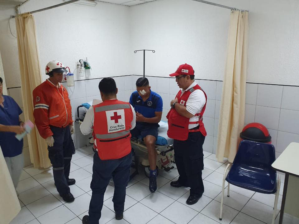 This photo, courtesy of Club Deportivo Motagua, shows Emilio Izaguirre, a Honduran player with the Motagua soccer club, amid Red Cross workers at a clinic as he gets his eye treated after he was hit by a rock thrown by fans of a rival team before a game in Tegucigalpa, Honduras, late Saturday, Aug. 17, 2019. The fight reportedly began when Olimpia fans attacked with stones and vandalized the bus carrying Motagua players to the stadium on Saturday. (Club Deportivo Motagua via AP)