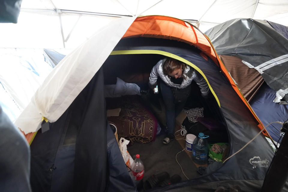 Hondurans Ana Morazan walks inside her tent at a migrant shelter Friday, May 20, 2022, in the border city of Tijuana, Mexico. Back-to-back hurricanes destroyed her home in Honduras in 2020, forcing her to join the millions of people uprooted by rising seas, drought, searing temperatures and other climate catastrophes. (AP Photo/Gregory Bull)