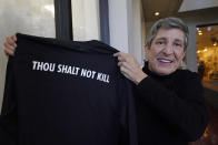 Suzi Altman holds a "New Miss" shirt with the biblical message, "Thou Shalt Not Kill," on its back, Nov. 23, 2021, in Jackson, Miss. The shirt and hats she produces, uses the same the cursive script as the Ole Miss logo that appears on football helmets, sports jerseys, marketing materials and all manner of bags, clothing and other merchandise licensed by the University of Mississippi. Altman applied for the New Miss trademark in July 2020, but the school has filed papers trying to block her from trademarking the "New Miss" logo. (AP Photo/Rogelio V. Solis)
