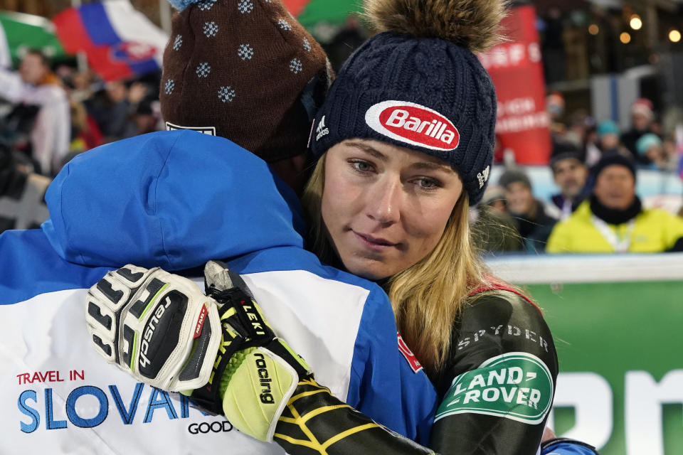 FILE - In this Jan. 14, 2020, file photo, United States' Mikaela Shiffrin embraces Italy's Livio Magoni, coach of Slovakia's Petra Vlhova, after completing an alpine ski women's World Cup slalom race in Flachau, Austria. When she's not winning races, two-time Olympic champion Mikaela Shiffrin unplugs by singing and playing guitar. Music was always a bond she shared with her late father, Jeff, who died on Feb. 2 after an accident at his home in Edwards, Colorado. (AP Photo/Giovanni Auletta, File)