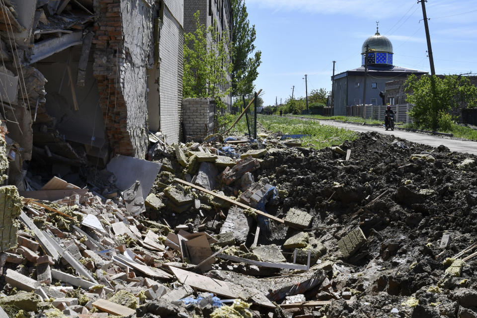 A crater of an explosion after Russian shelling is seen next to a damaged apartment building in Bakhmut, Donetsk region, Ukraine, Thursday, May 12, 2022. (AP Photo/Andriy Andriyenko)