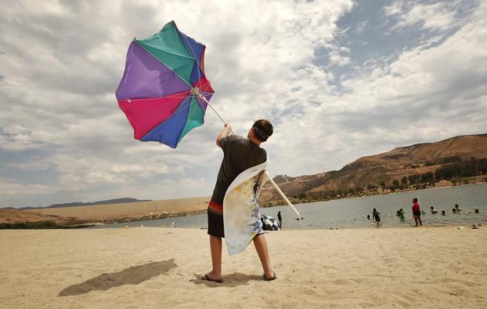 CASTAIC, CA - JULY 08: Zachary Pruett, 10, catches wind with this umbrella as he was putting it away after he and his Mom Amanda Pruett, from Santa Clarita finish their morning at Castaic Lake Lagoon. The pair came to &quot;Cool off before the sun becomes dangerous.&quot; Said Amanda. Temperatures began to soar Thursday morning as a new heatwave is predicted to bring dangerously hot weather to California&#39;s inland regions this week, with relentlessly high temperatures that continue to torment the west coast. Castaic Lake Lagoon is now open daily 10am to 6pm. Castaic Lake Lagoon on Thursday, July 8, 2021 in Castaic, CA. (Al Seib / Los Angeles Times).