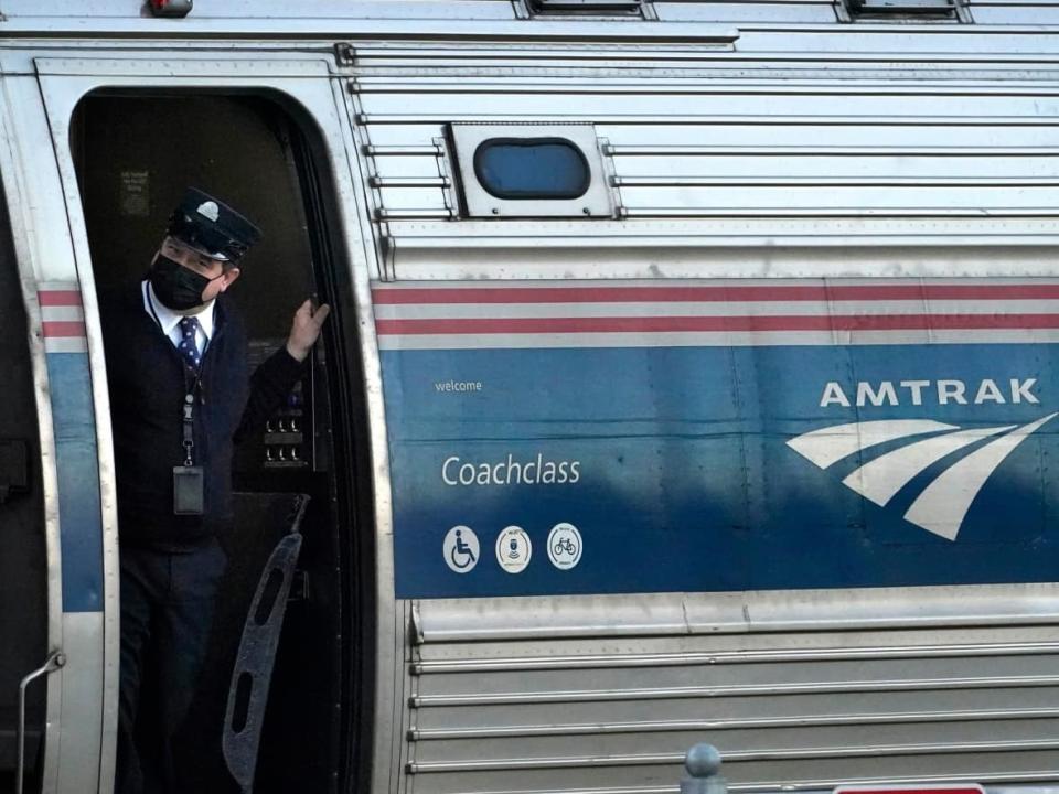 A conductor makes sure all is clear as an Amtrak train pulls out of the station in Freeport, Maine in December 2021. The U.S. government-owned service will resume round trips from Vancouver to Portland starting on March 7. (Robert F. Bukaty/AP Photo - image credit)
