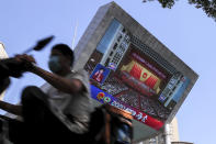 A food delivery worker wearing a face mask to protect against the spread of the new coronavirus passes by a TV screen showing the closing ceremony of the National People's Congress in a news report, in Beijing, China, Thursday, May 28, 2020. China's ceremonial legislature on Thursday endorsed a national security law for Hong Kong that has strained relations with the United States and Britain. (AP Photo/Andy Wong)