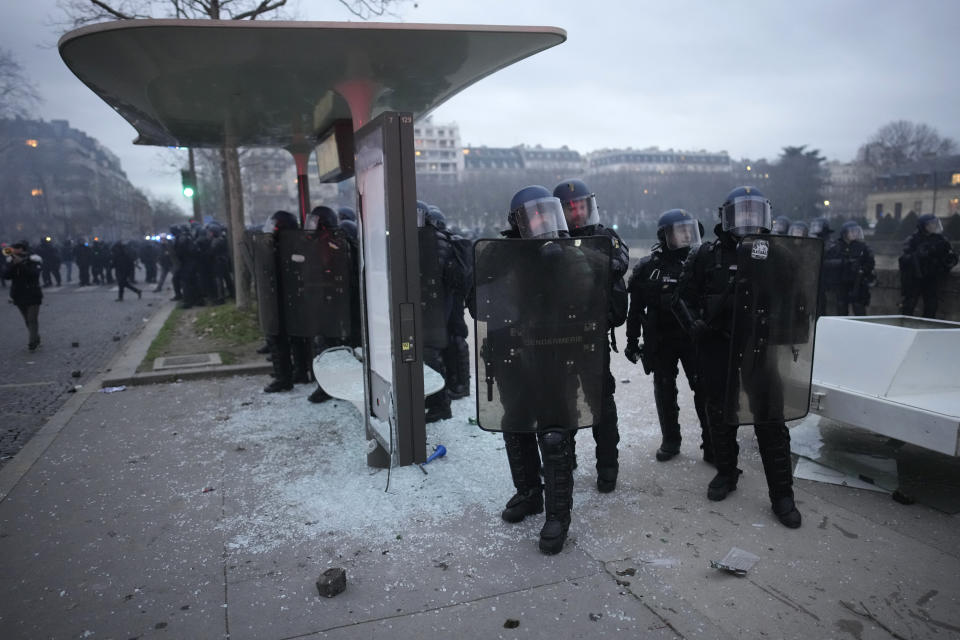 Riot police officers stand by a damaged bus stop after incidents during a demonstration against plans to push back France's retirement age, Tuesday, Jan. 31, 2023 in Paris. Labor unions aimed to mobilize more than 1 million demonstrators in what one veteran left-wing leader described as a "citizens' insurrection." The nationwide strikes and protests were a crucial test both for President Emmanuel Macron's government and its opponents. (AP Photo/Christophe Ena)