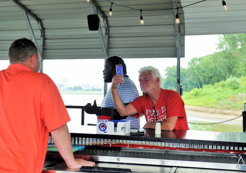 A pair of customers horse around with bartender "CB Dan" on the Dive Barge on Thursday, Aug. 3, 2023.