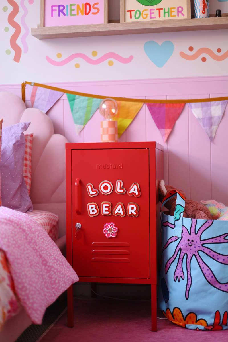 Pink paneling up half wall, red locker next to pink flower headboard twin bed, triangle flag ribbon, squiggle and heart doodles on wall