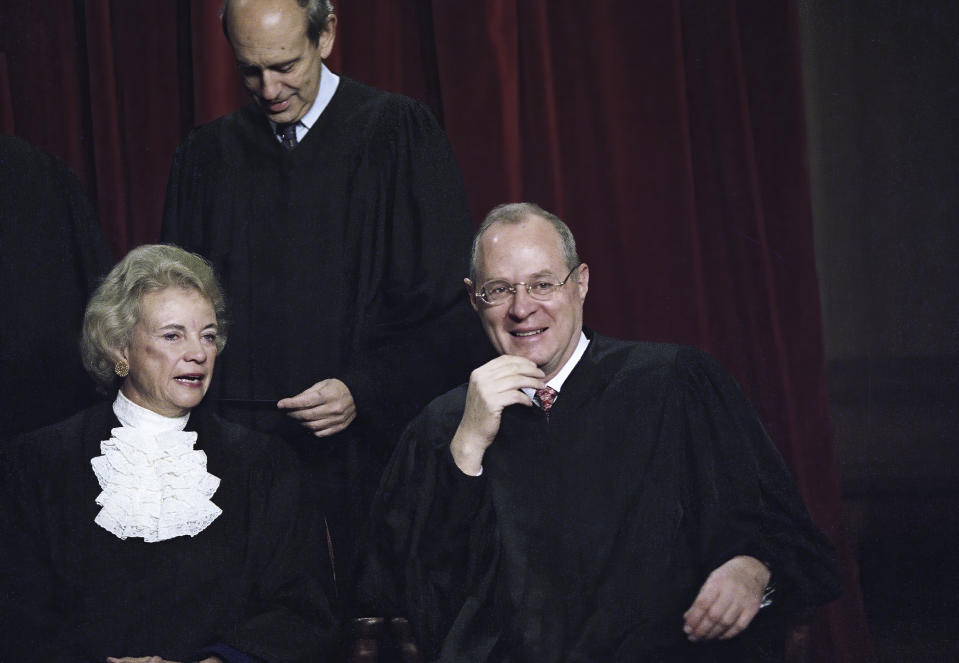 FILE - Associate Supreme Court Justices Sandra Day O' Connor and Anthony Kennedy chat as the entire court has their portrait taken on Nov. 10, 1994, in Washington. For years, the Supreme Court moved to the left or right only as far as Justices O'Connor and Kennedy allowed. They held pivotal votes on a court closely divided between liberals and conservatives. Now, though, a more conservative court that includes two men who once worked for Kennedy is taking direct aim at major opinions written by the two, now retired, justices.(AP Photo/J. Scott Applewhite, File)