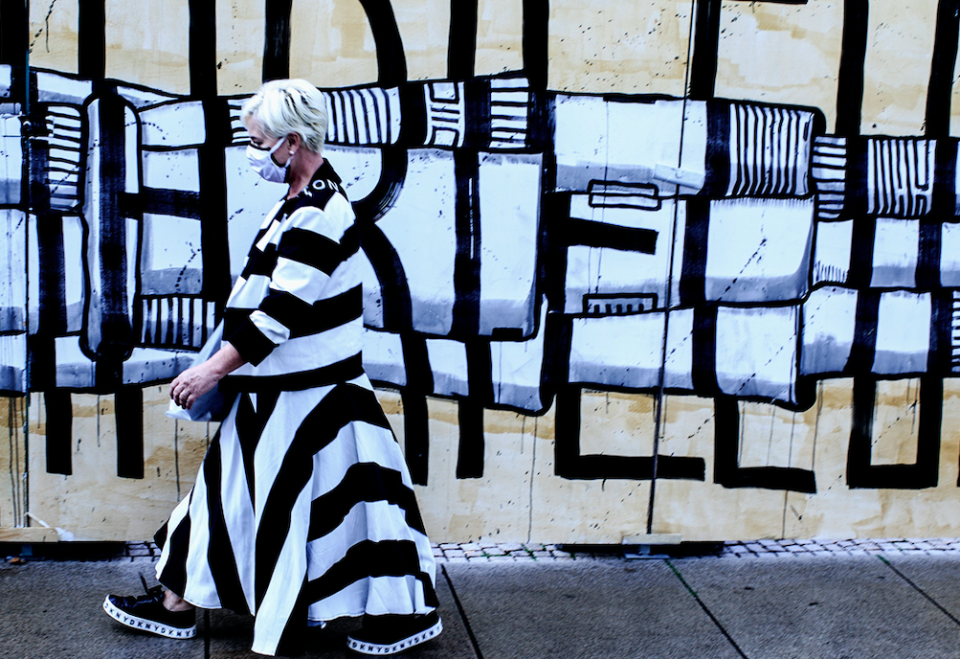 A woman's dress perfectly matches the graffiti she walks past.