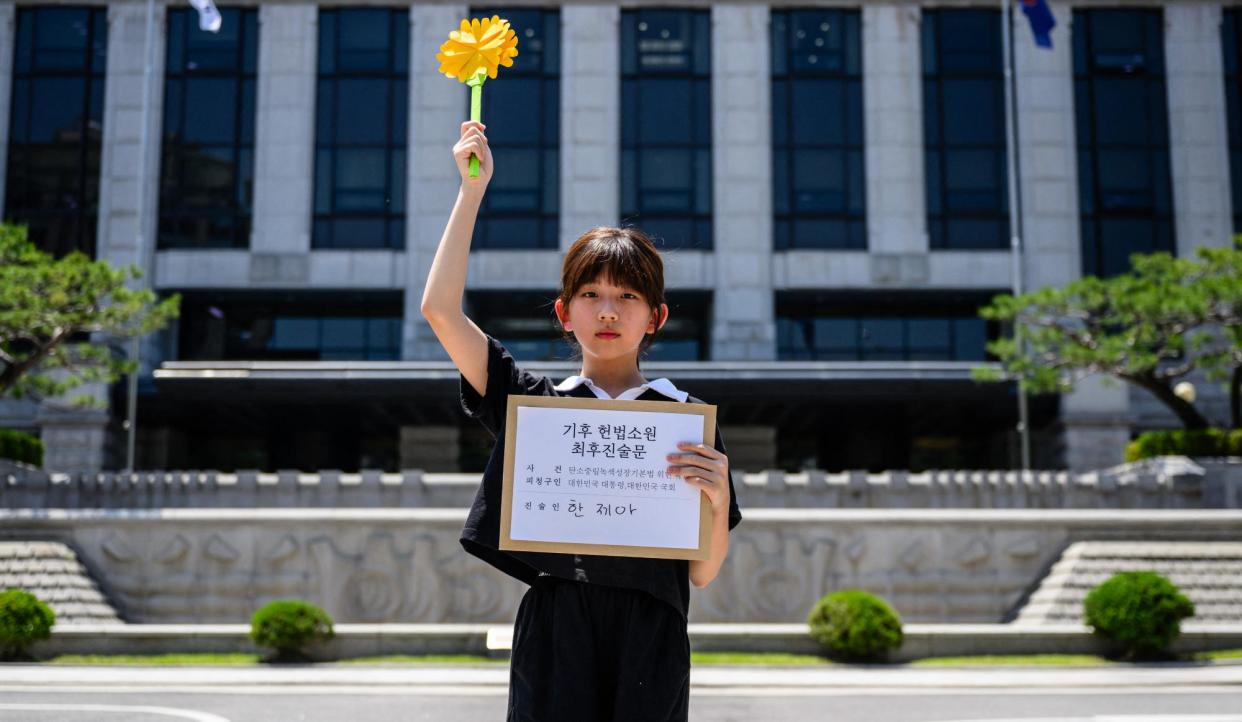 <span>Jeah Han holds a file containing her closing argument outside South Korea’s constitutional court in Seoul in May 2024. The climate campaigner says she has felt the direct impacts of the climate crisis.</span><span>Photograph: Anthony Wallace/AFP/Getty Images</span>