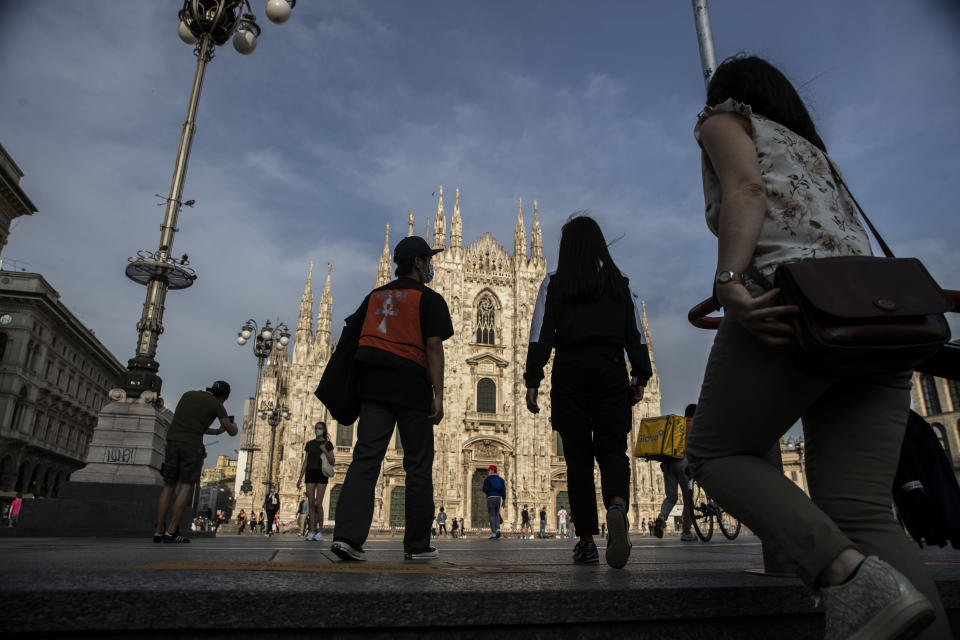 People walk in front of the Duomo gothic cathedral in Milan, Italy, Monday, May 18, 2020.. On Monday, Italians enjoyed a first day of regained freedoms, including being able to sit down at a cafe or restaurant, shop in all retail stores or attend church services such as Mass. (AP Photo/Luca Bruno)