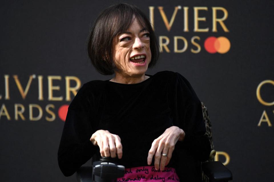 liz carr wearing a black top and magenta skirt on the red carpet