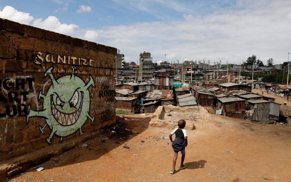 A boy walks past graffiti of the virus in Nairobi - Baz Ratner/Reuters