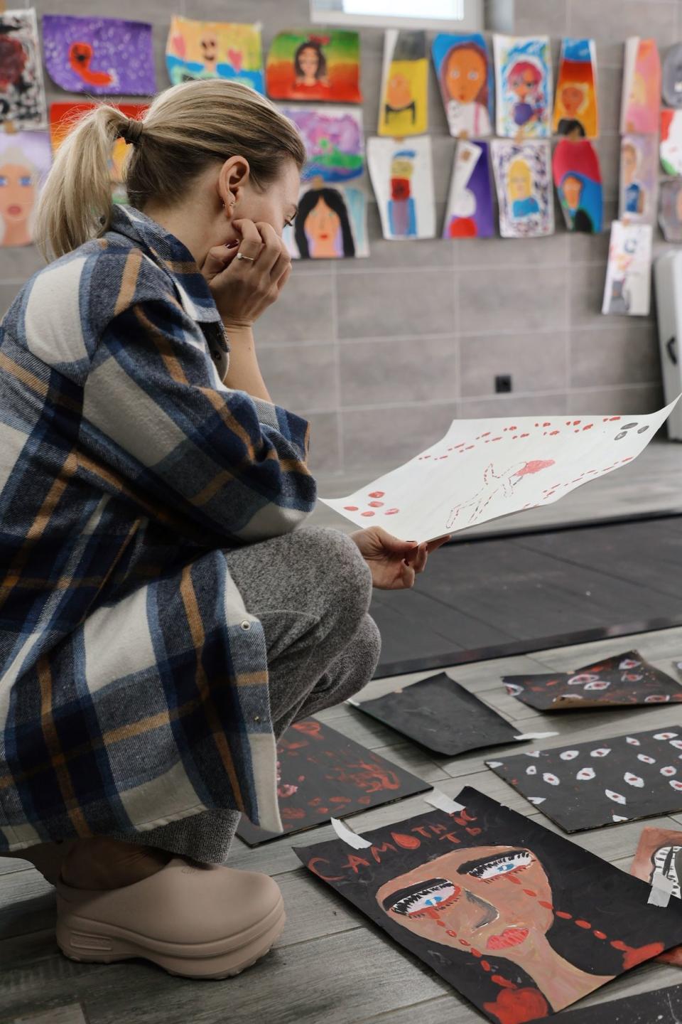 Gen. Ukrainian founder Oksana Lebedeva looks at the children's paintings of their fears in camp in western Ukraine. (Gen.Ukrainian)