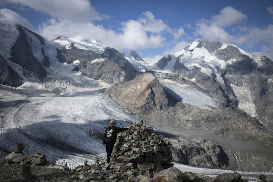 A person stands in front of the Bernina mountain group with the Pers and Morteratsch glaciers in Pontresina, Switzerland, Wednesday, August 10, 2022. (Gian Ehrenzeller/Keystone via AP)