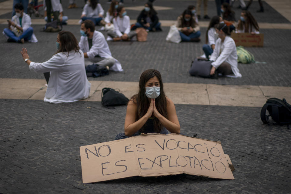 Medical residents take part on a protest against their working conditions during a strike in Barcelona, Spain, Thursday, Oct. 22, 2020. Spain has reported 1 million confirmed infections — the highest number in Western Europe — and at least 34,000 deaths from COVID-19, although experts say the number is much higher since many cases were missed because of testing shortages and other problems. Banner reads in Spanish: "it is not a vocation but exploitation". (AP Photo/Emilio Morenatti)