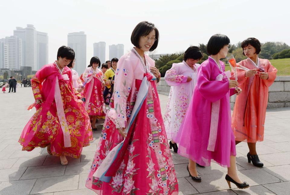 North Korean women wearing traditional costumes walk towards bronze statues of North Korea's late founder Kim Il Sung and late leader Kim Jong Il at Mansudae in Pyongyang