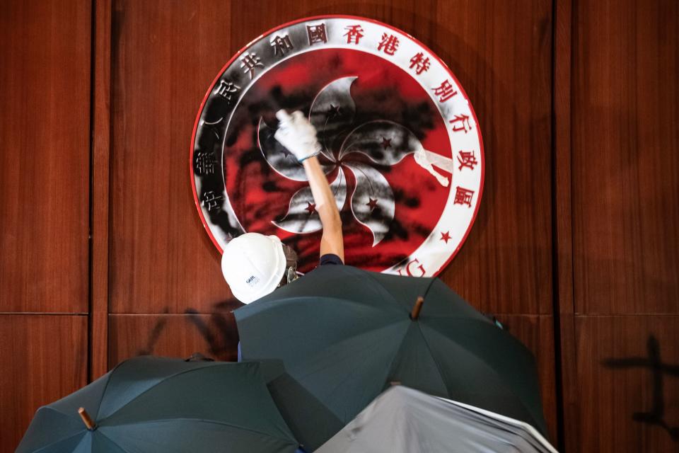 A protester defaces the Hong Kong emblem after protesters broke into the government headquarters in Hong Kong on July 1, 2019, on the 22nd anniversary of the city's handover from Britain to China. - Hundreds of protesters stormed Hong Kong's parliament late on July 1 as the territory marked its China handover anniversary, ransacking the building and daubing its walls with graffiti as the city plunged into unprecedented depths of political chaos. (Photo by Philip FONG / AFP)        (Photo credit should read PHILIP FONG/AFP/Getty Images)