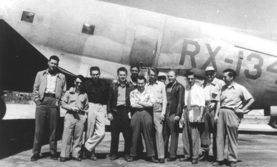 A group of men in front of a plane