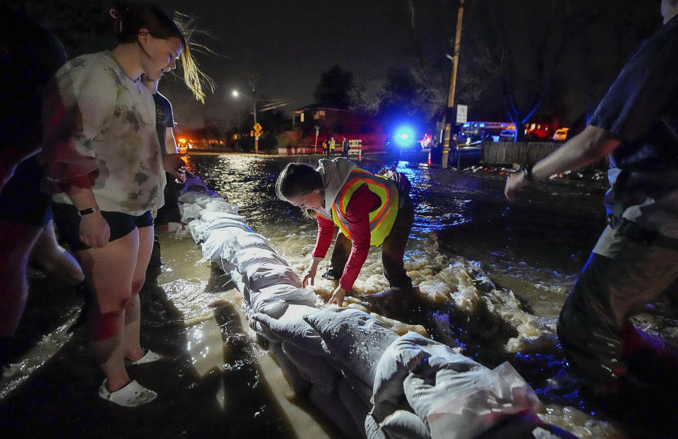 Mayor Erin Mendenhall and numerous volunteers pile sandbags along 1700 South in Salt Lake City in an effort to divert the rising flow of Emigration Creek through Wasatch Hollow Park on Wednesday, April 12, 2023. As rapid snowmelt and possible April showers stoke fears of heavy flooding in the Northern Plains, state officials are announcing flood response plans, and residents are assembling thousands — if not hundreds of thousands — of sandbags to combat floods themselves. (Francisco Kjolseth/The Salt Lake Tribune via AP)