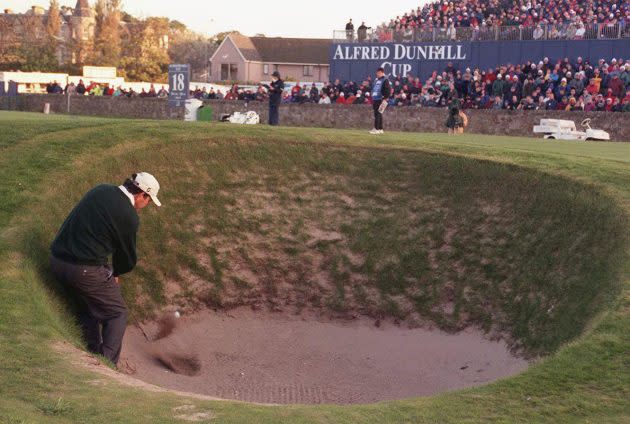 Golfer plays out of a pot bunker on a links course