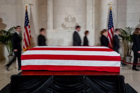 People walk past the late Supreme Court Justice John Paul Stevens as he lies in repose in the Great Hall of the Supreme Court in Washington