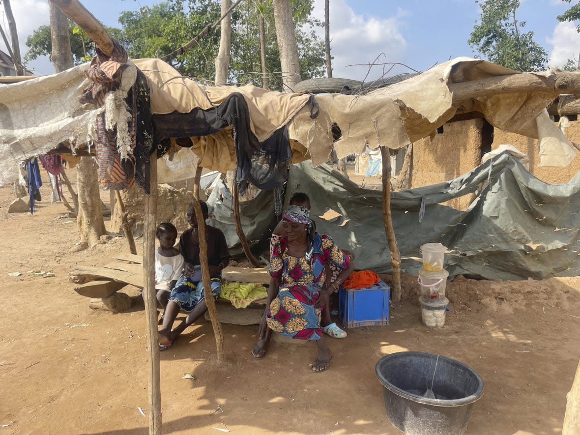 Rifkatu Andruwus, 66, sits with family members, in front of her makeshift home at the Durami camp for the displaced, in Abuja , Nigeria, Friday, June 9, 2023. Hundreds remain homeless in Nigeria’s capital of Abuja after losing their shanties to government bulldozers. Authorities say the demolitions seek to rid the city of crime and restore Abuja’s master plan, a conceptual layout meant to promote growth of this oil-rich Western African nation. (AP Photo/Chinedu Asadu)