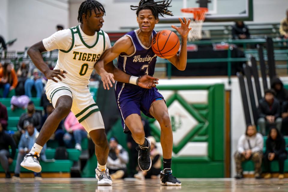 Indianapolis Crispus Attucks High School senior Demetrius Jenkins (0) defends Indianapolis Washington High School senior Malique Starks (3) as he brings the ball up court during the first half of an Indianapolis Boys Basketball Tournament semi-final game, Saturday, Jan. 20, 2024, at Arsenal Tech High School.