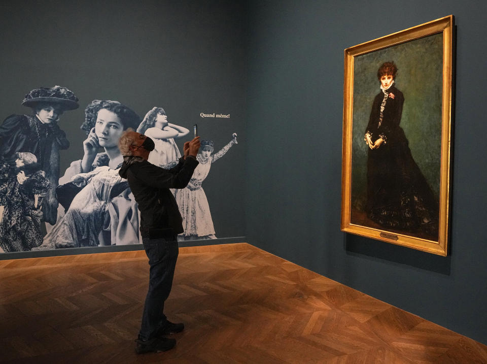 A visitor takes a photograph of the painting where Sarah Bernhardt is represented in the role of Berthe de Savigny in The Spinx, by Philippe Parrot, 1874, during the "Sarah Bernhardt, and the woman created the star" exhibition at the Petit Palais museum in Paris, Friday, April 28, 2023. Inside Paris’ Petit Palais museum, the public is now discovering the madcap jigsaw puzzle of gothic stories, costumes, recordings, films, photos, jewels, sculptures, and personal objects for the first time together that made the unclassical beauty the object of fascination from Berlin, to London and New York. (AP Photo/Michel Euler)