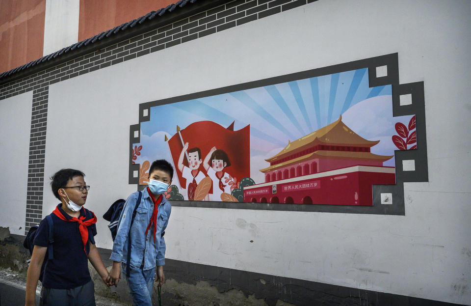 Image: Chinese boys pass a patriotic banner as they walk home together from a local elementary school after classes (Kevin Frayer / Getty Images file)