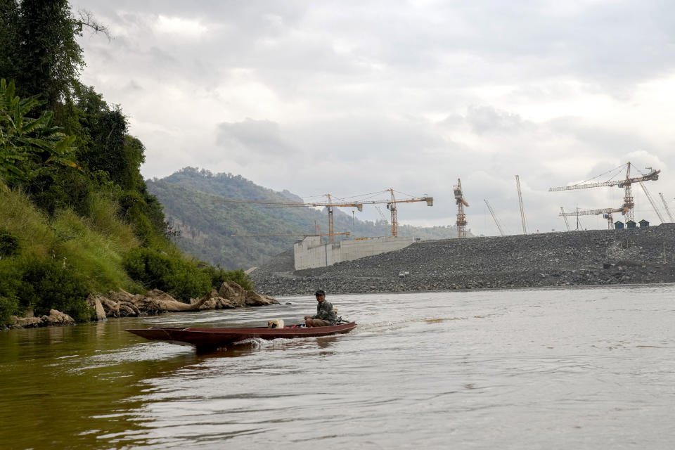 People on a boat move in Mekong river in front of construction site of Luang Prabang dam in Luang Prabang, Laos, Sunday, Jan. 28, 2024. Luang Prabang was named a UNESCO World Heritage Site nearly 30 years ago, but a multibillion-dollar dam project is raising questions that could deprive the city of its coveted status and prompting broader concerns the Mekong River could be ruined by multiple dams that are being planned.(AP Photo/Sakchai Lalit)