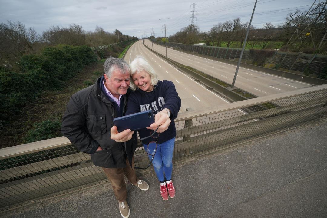 Fiona and Patrick Potter, residents of West Byfleet take a selfie on the Parvis Road bridge in Byfleet, that crosses over a closed section of the M25 between Junctions 10 and 11, while a bridge is demolished and a new gantry is installed. Picture date: Saturday March 16, 2024.