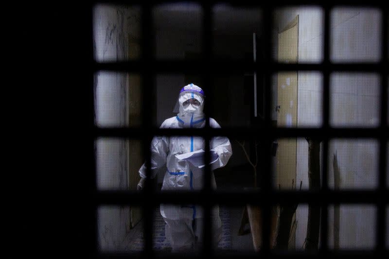 FILE PHOTO: A pandemic prevention worker in a protective suit approaches an apartment in a building that went into lockdown as coronavirus disease (COVID-19) outbreaks continue in Beijing