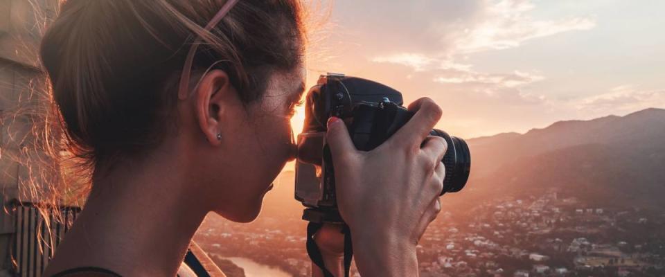 Female photographer, taking pictures of mountain landscape at sunset in Georgia