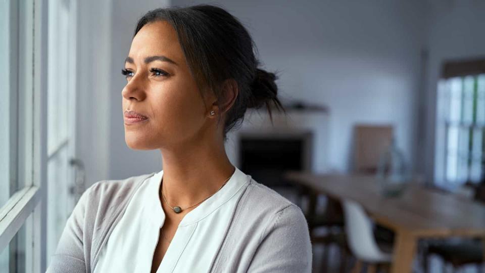 Young mixed-race woman looking out of the window with a look of consternation on her face