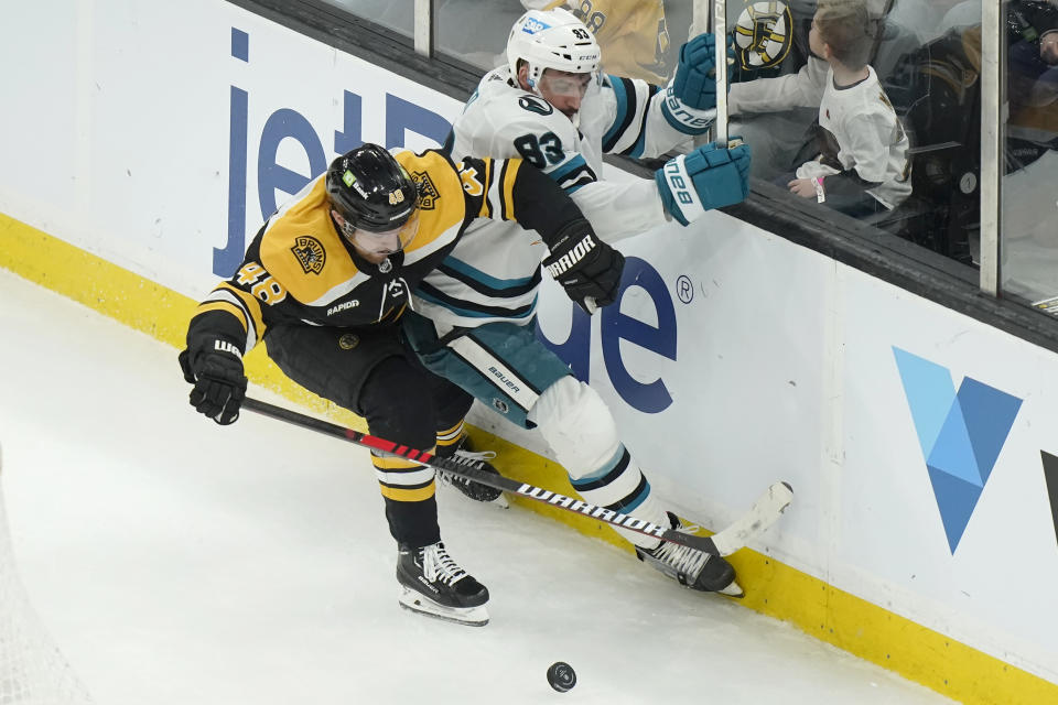 Boston Bruins defenseman Matt Grzelcyk and San Jose Sharks left wing Matt Nieto (83) vie for control of the puck in the second period of an NHL hockey game, Sunday, Jan. 22, 2023, in Boston. (AP Photo/Steven Senne)